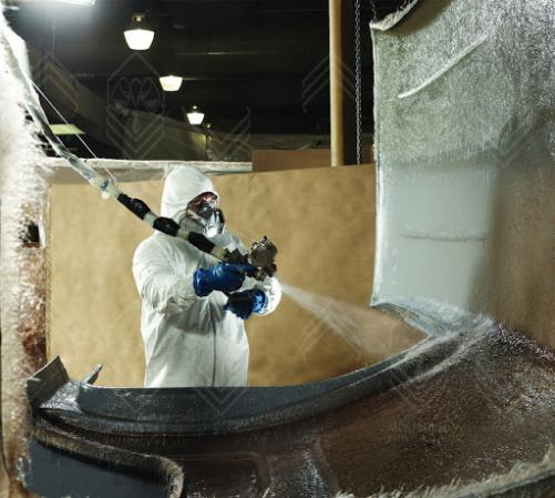 عکس شخصی که در حال پاشش رزین برای ساخت قایق با فایبرگلاس است.